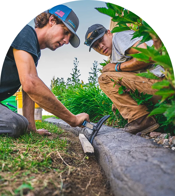 Two men working on garden edging installation.