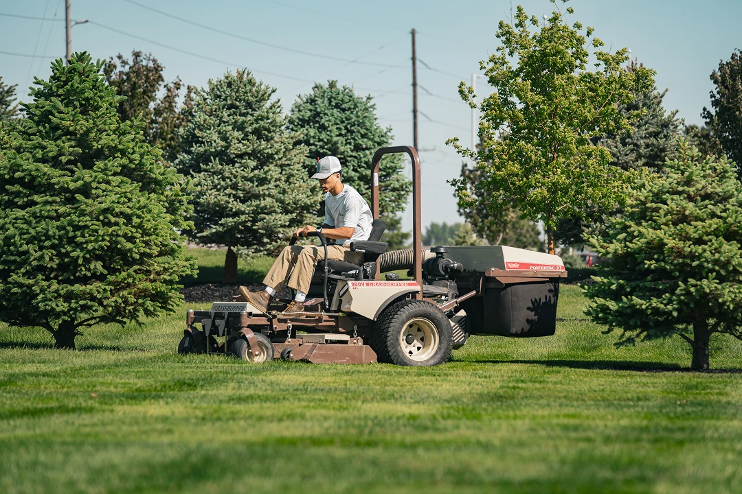 Person mowing grass on a riding mower.