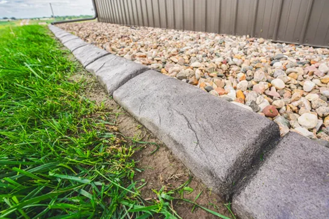 Stone border between grass and gravel area.