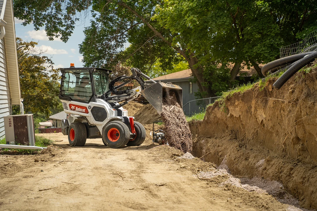 Skid steer loader moving dirt on construction site.